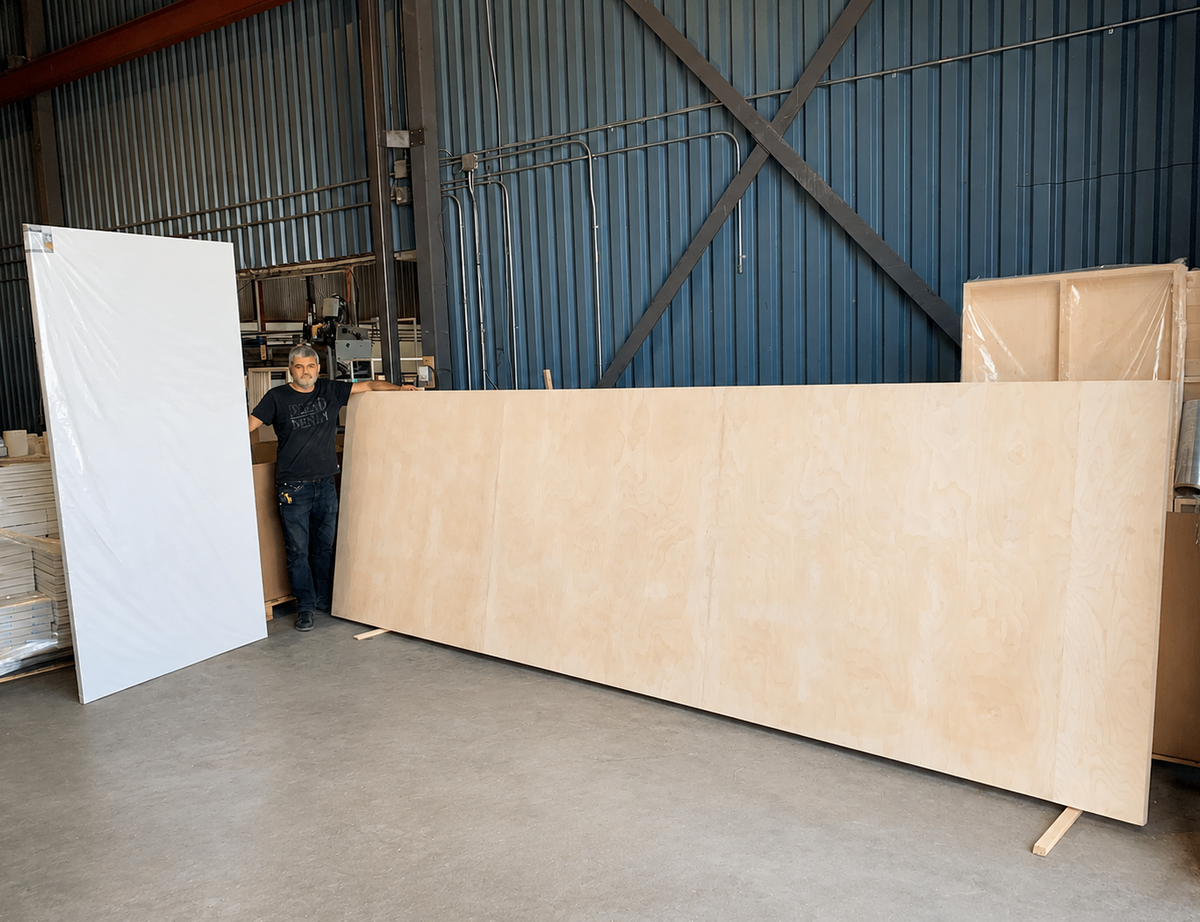 A member of the Apollon team beside an oversized birch panel