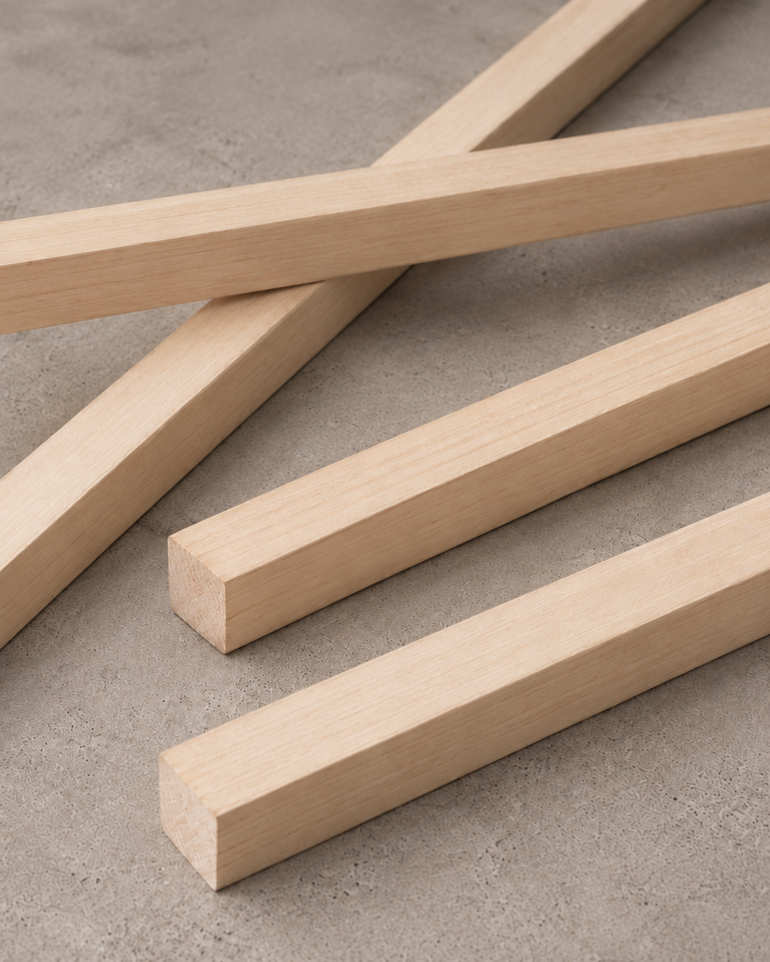 Natural wood moulding lengths stacked diagonally in a close-up view.
