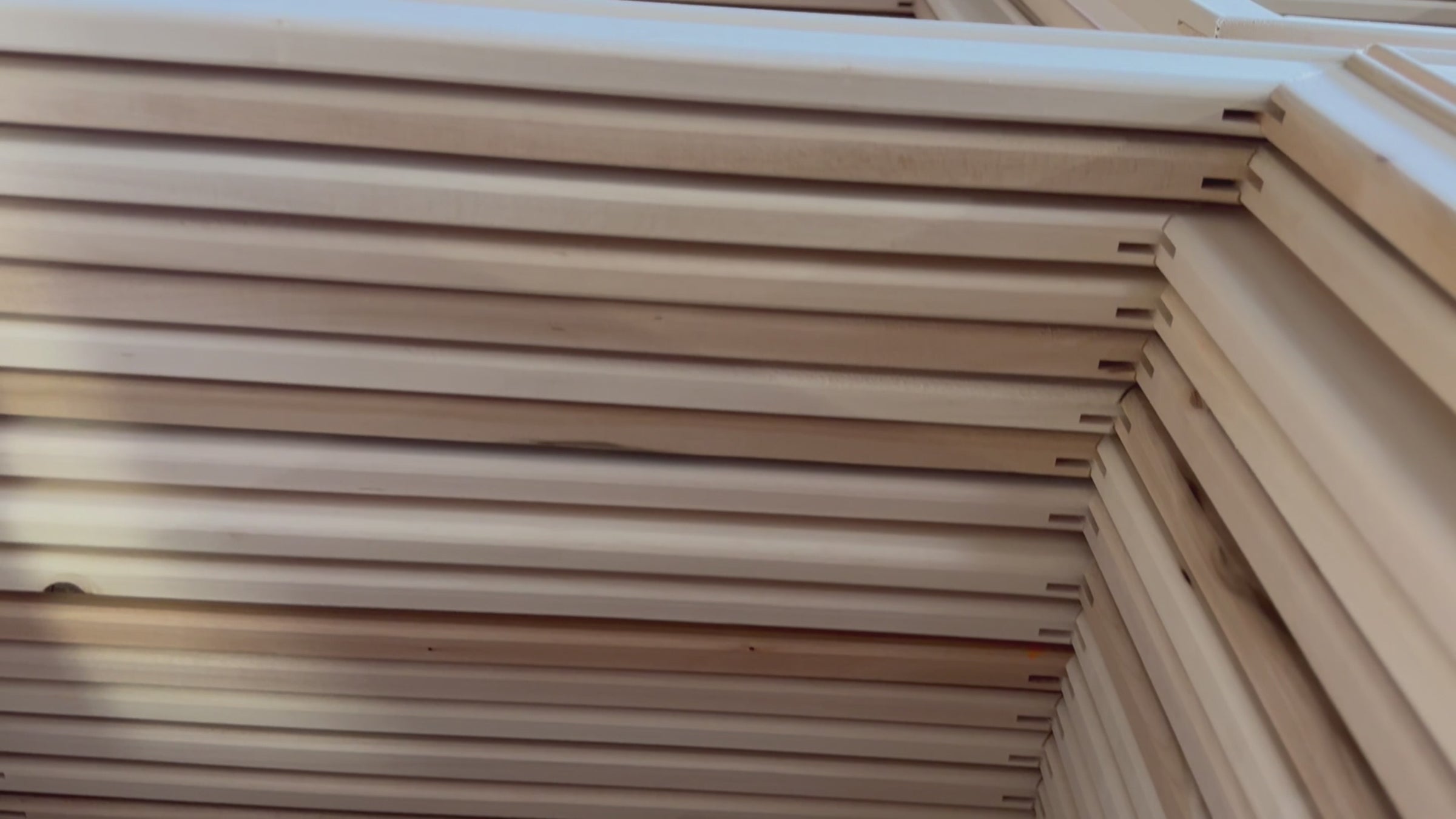A gloved worker staples canvas onto a wooden stretcher frame with a pneumatic stapler in the Apollon workshop.