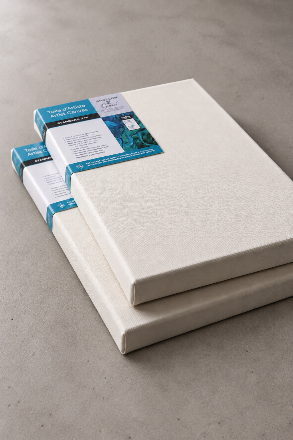 Stacked standard cotton artist canvases on a neutral studio surface.