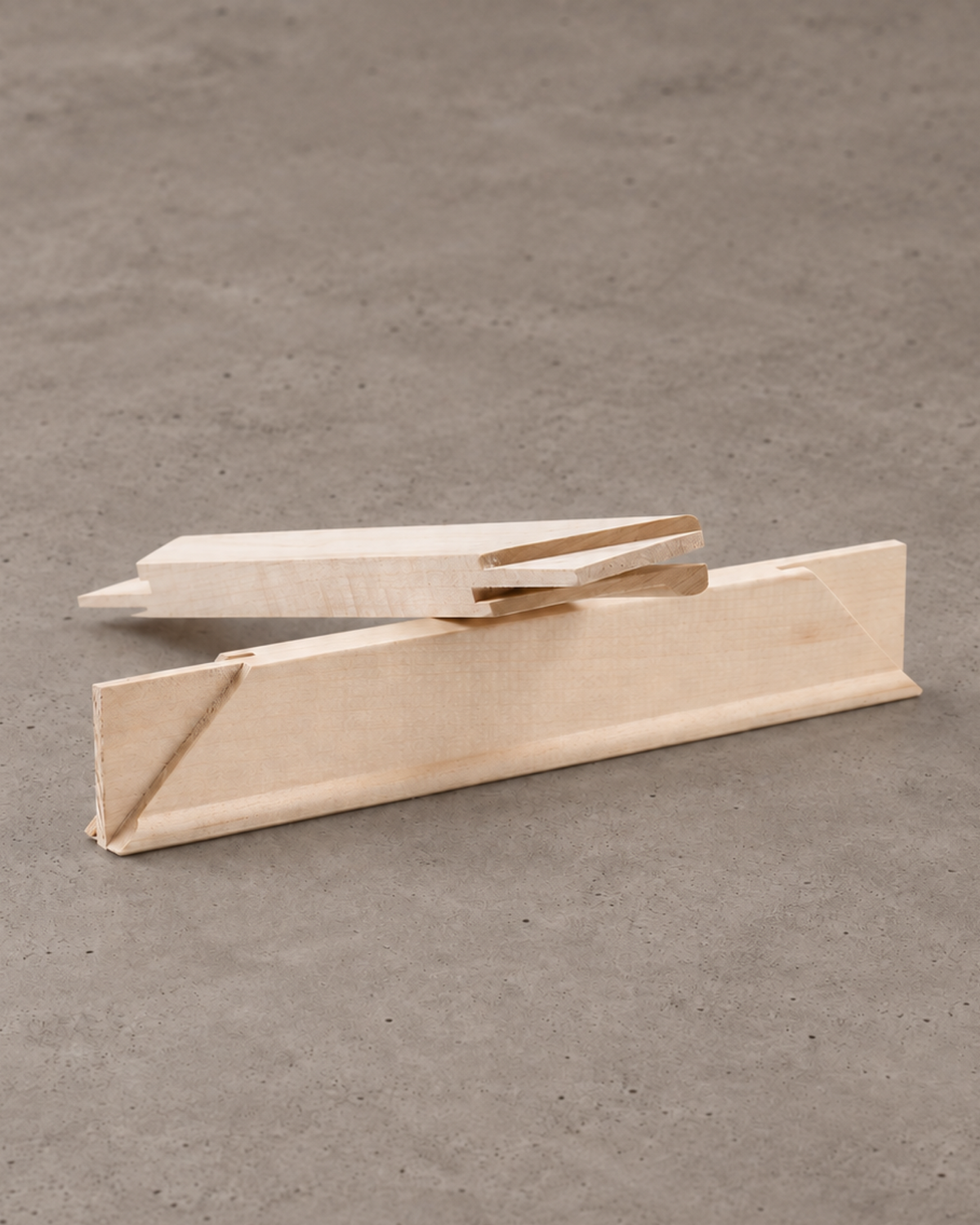 Natural wood stretcher bars stacked diagonally on a neutral concrete surface.