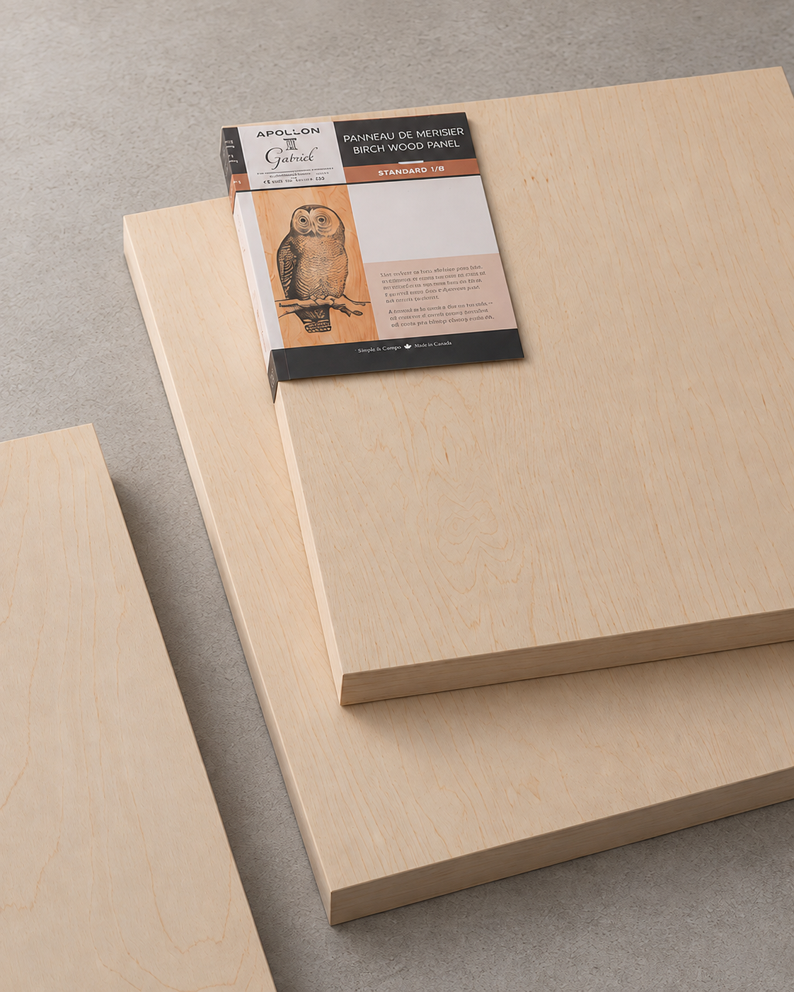 Three light natural wood panels stacked diagonally on a gray surface, with a packaged sheet labeled Apollon Gotrick Birch Wood Panel in the center.